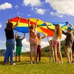 Kids playing in the field with a colorful sheet